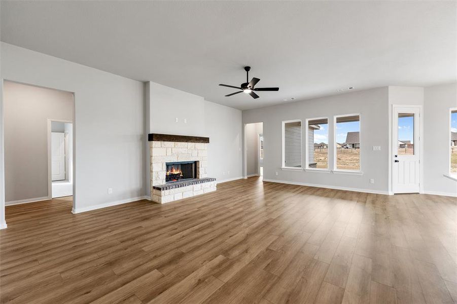 Unfurnished living room with a fireplace, wood finished floors, and a ceiling fan Unfurnished living room with a fireplace, wood finished floors, and a ceiling fan