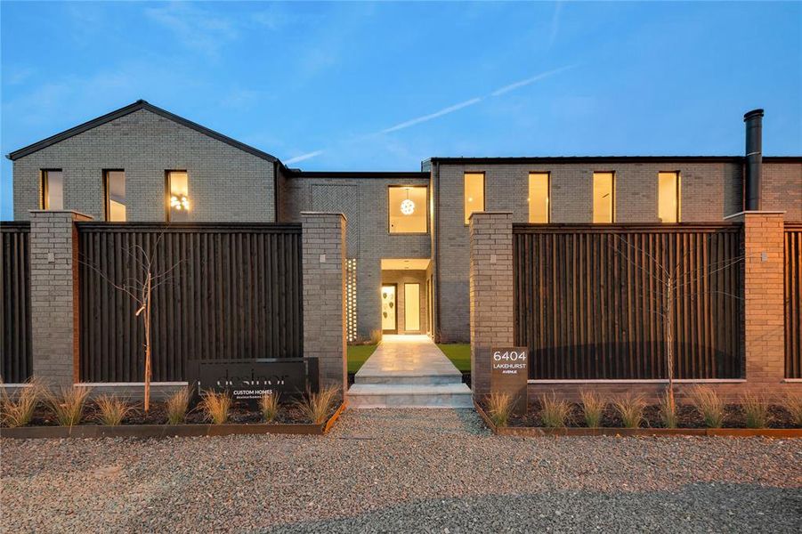 View of front of home featuring brick siding and custom cedar perimeter privacy fence.