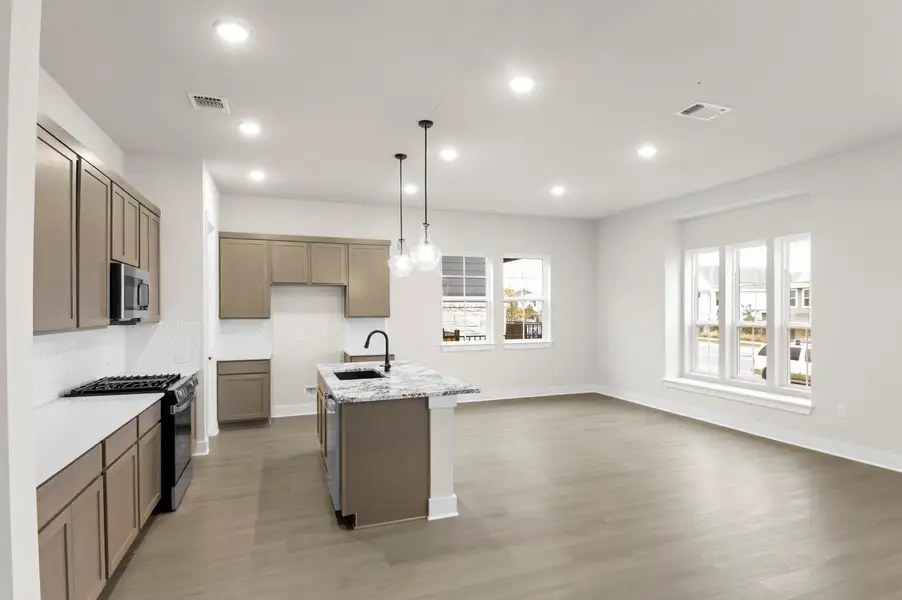 Kitchen featuring gas stove, hanging light fixtures, recessed lighting, an island with sink, and light wood-type flooring