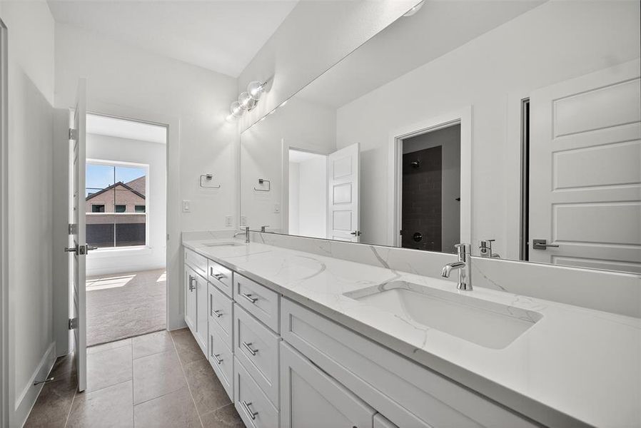 Bathroom featuring double vanity, light tile patterned floors, and a shower