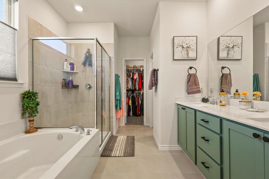 Full bath featuring a shower stall, double vanity, a bath, tile patterned flooring, and a spacious closet Full bath featuring a shower stall, double vanity, a bath, tile patterned flooring, and a spacious closet