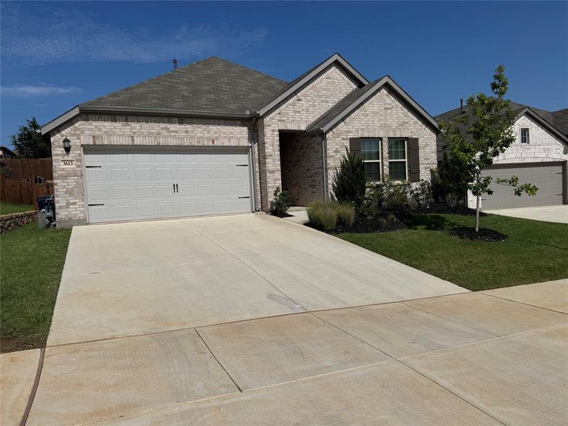 Contemporary single-story residence featuring light-colored brick veneer, a dark gray shingle roof, and an attached two-car garage Contemporary single-story residence featuring light-colored brick veneer, a dark gray shingle roof, and an attached two-car garage