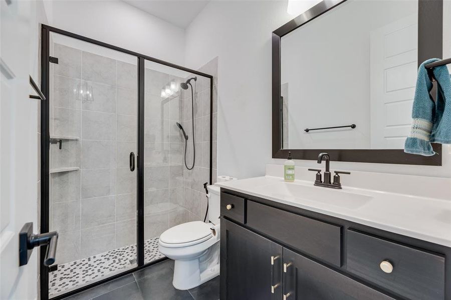 Bathroom featuring vanity, dark tile patterned floors, and a shower stall