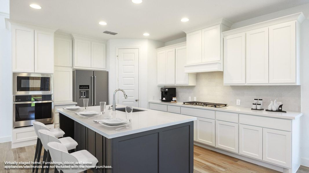 Kitchen with white cabinetry, recessed lighting, stainless steel appliances, light wood-style floors, and light stone counters Kitchen with white cabinetry, recessed lighting, stainless steel appliances, light wood-style floors, and light stone counters