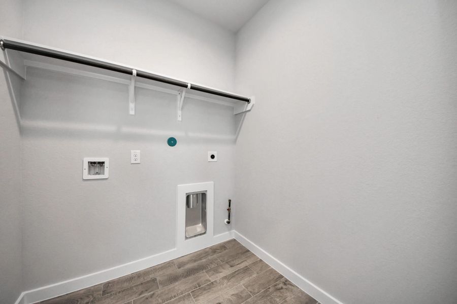 A perfect blend of functionality and comfort. Capture the essence of easy living with a first-floor laundry room, thoughtfully equipped with shelving for effortless organization. Both electric and gas connections available. Sample photo of completed home with similar floor plan. Actual colors and selections may vary.