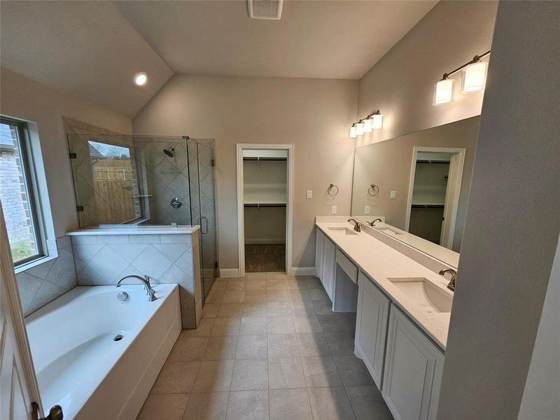 Master bathroom with Monet quartz dual vanity, garden tub, and separate tile shower with frameless glass.