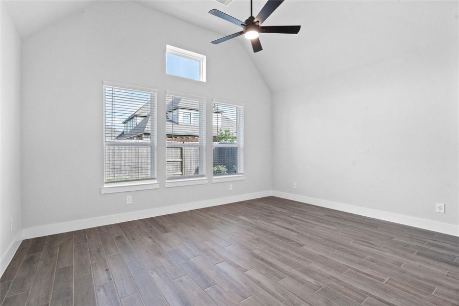 Relax and unwind after a long day in this impressive primary suite! This generously sized room offers tile flooring, neutral-toned paint, high ceilings with a ceiling fan, and large windows for added comfort and tranquility.