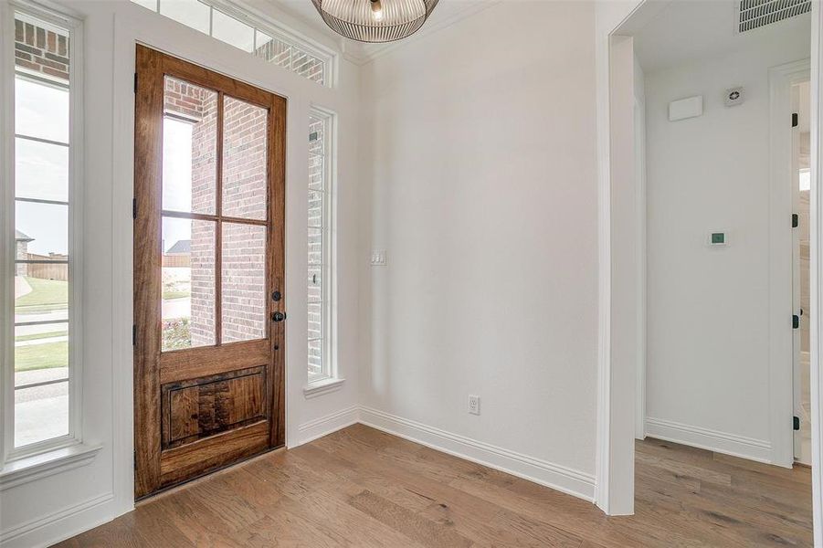 Foyer entrance with light hardwood / wood-style floors, ornamental molding, and a healthy amount of sunlight