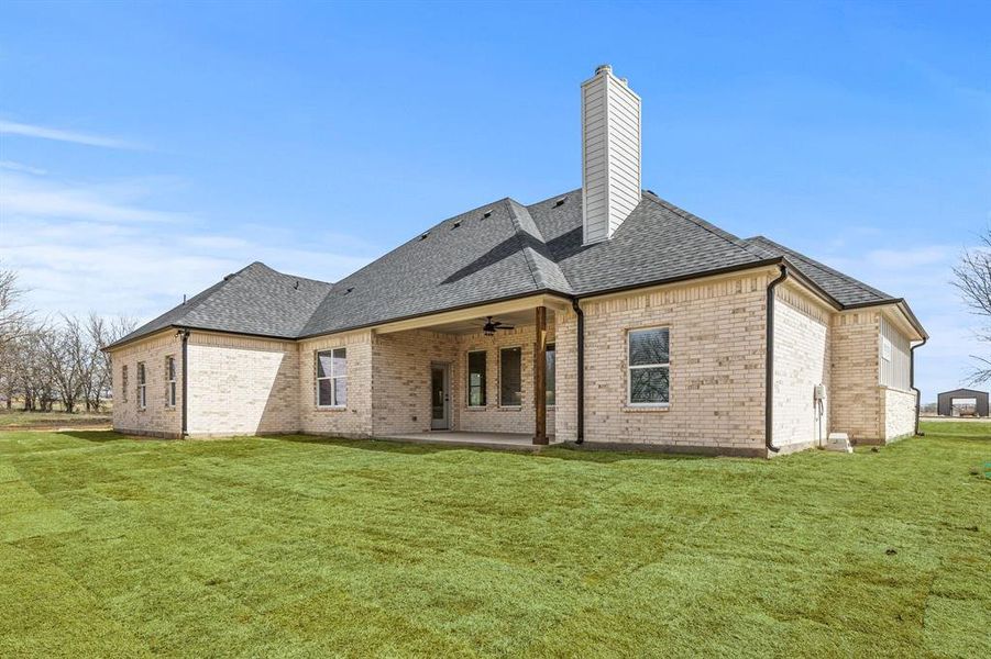 Rear view of house with roof with shingles, brick siding, a patio area, a ceiling fan, and a yard Rear view of house with roof with shingles, brick siding, a patio area, a ceiling fan, and a yard