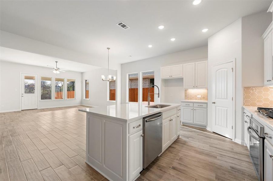 Kitchen featuring backsplash, ceiling fan, a chandelier, white cabinetry, and recessed lighting