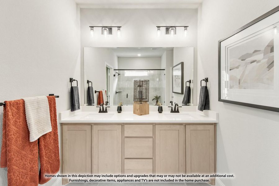 Bathroom with double vanity, large mirror, light wood cabinets, and glass shower in background
