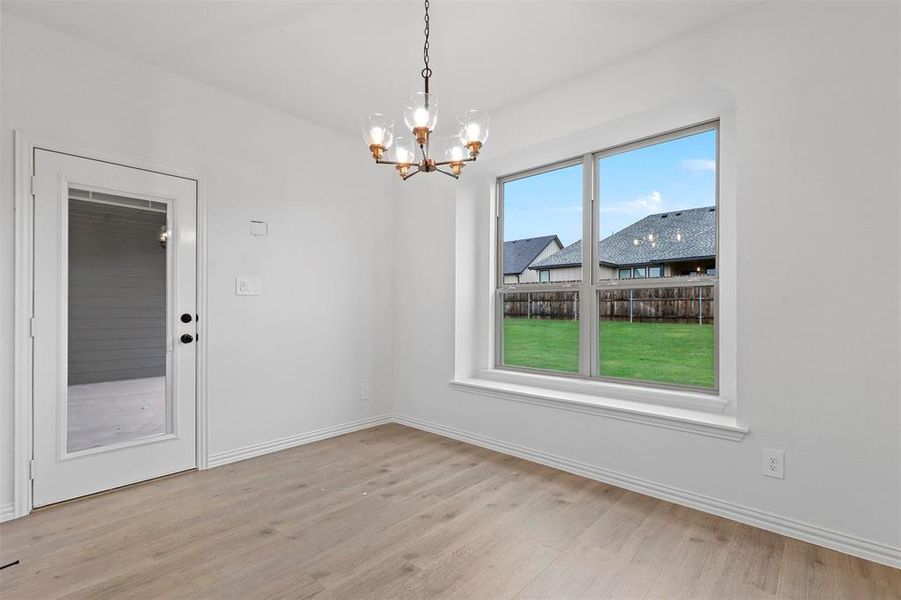 Unfurnished dining area featuring light hardwood / wood-style floors and a notable chandelier