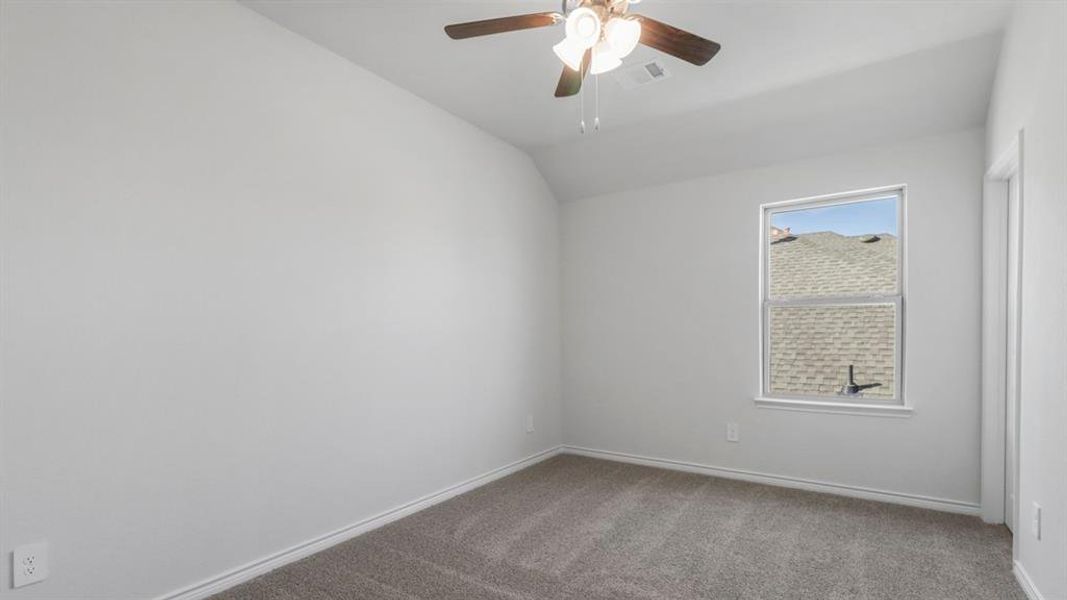 Spare room with light colored carpet, vaulted ceiling, and ceiling fan