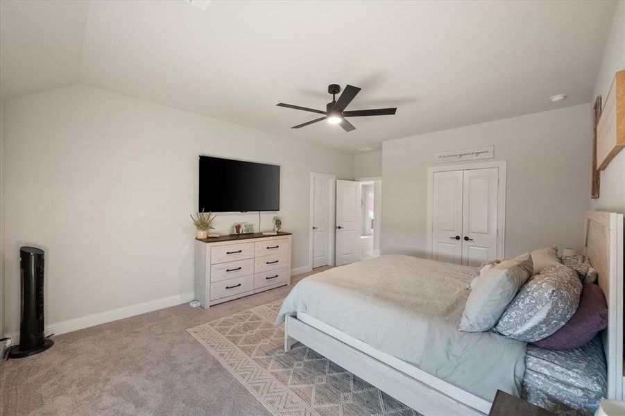 Bedroom featuring light carpet, a ceiling fan, and a closet