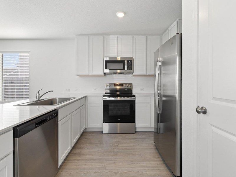 Kitchen with stainless steel appliances, white cabinetry, light wood finished floors, recessed lighting, and a peninsula