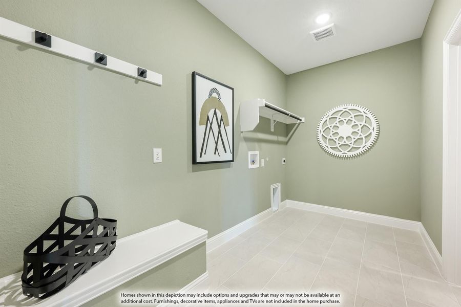 Mudroom with sage green walls, wall-mounted coat hooks, white bench, and tile floors