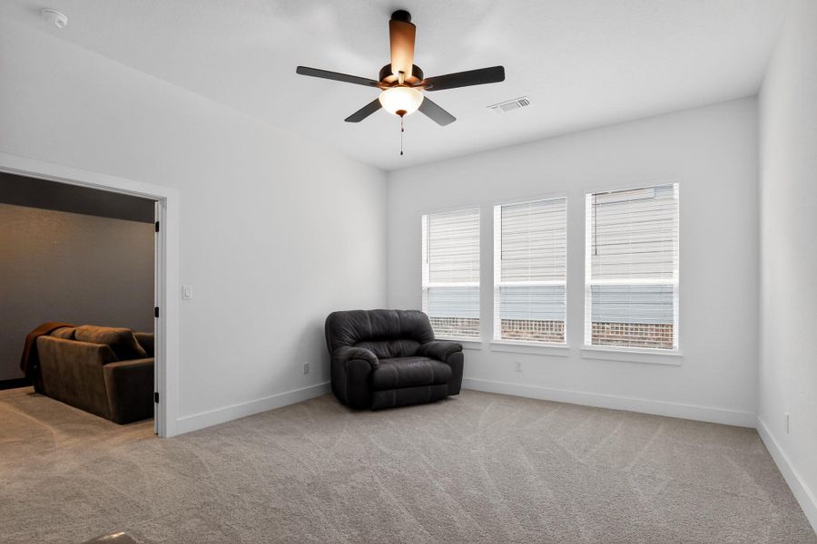 Carpeted room featuring white walls, three windows with blinds, and a ceiling fan with integrated lighting Carpeted room featuring white walls, three windows with blinds, and a ceiling fan with integrated lighting
