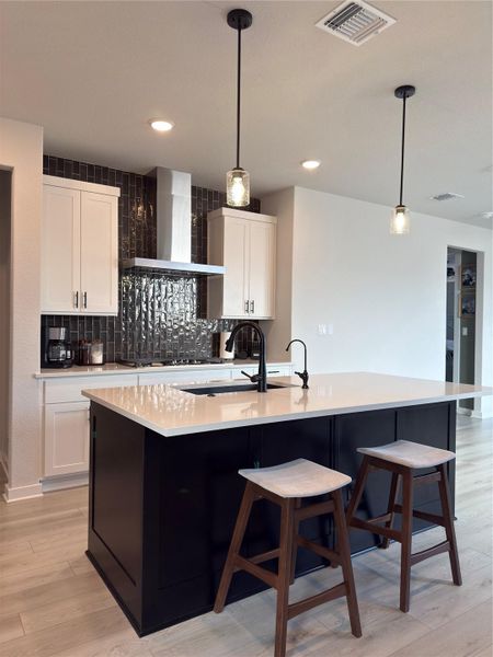 Contemporary kitchen featuring a large island with a light-toned countertop, a black base, and built-in sink