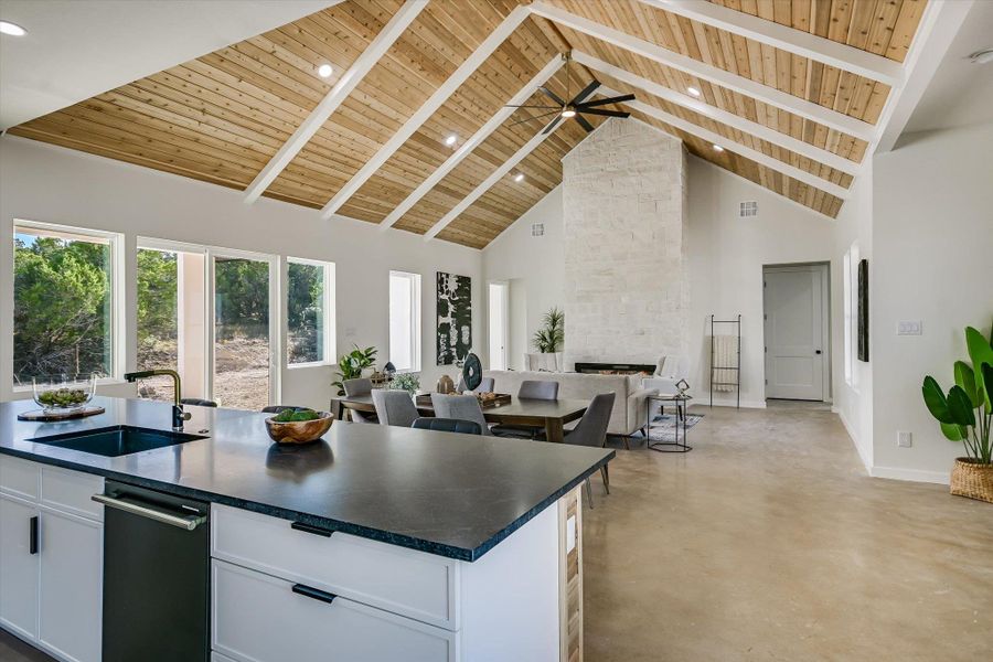 Kitchen featuring high vaulted ceiling, a wood ceiling with exposed beams, a fireplace, white cabinets, and open floor plan