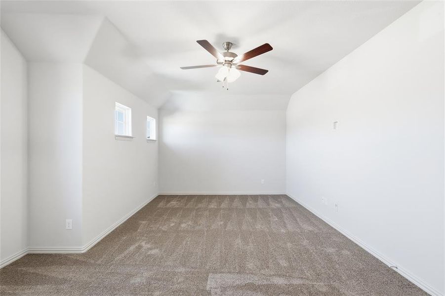 Spare room with light colored carpet, a ceiling fan, and vaulted ceiling