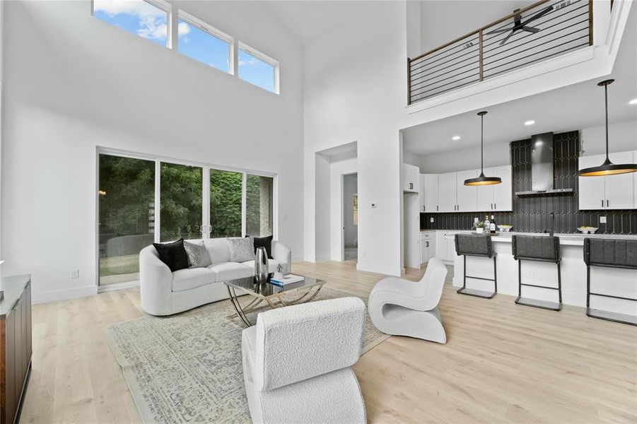 Living area featuring a high ceiling and light wood-style floors Living area featuring a high ceiling and light wood-style floors