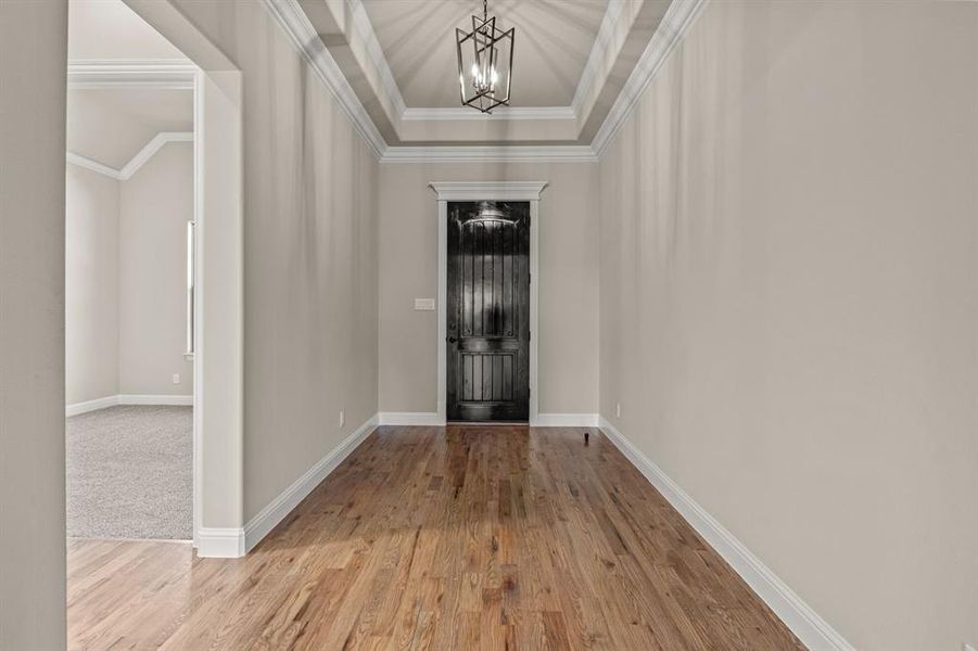 Entryway with an inviting chandelier, crown molding, vaulted ceiling, and light hardwood / wood-style flooring