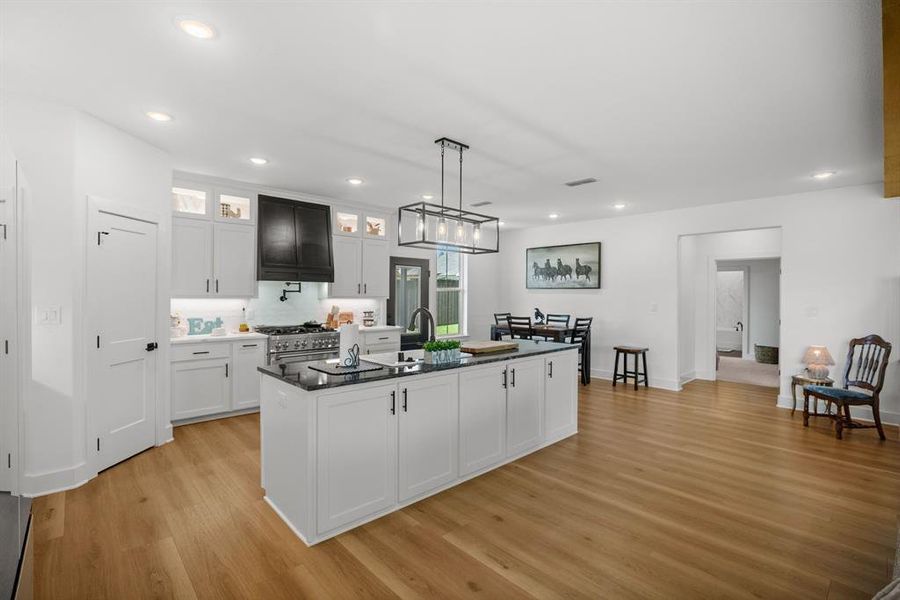 Kitchen featuring stainless steel range, light wood-style flooring, white cabinets, glass insert cabinets, and recessed lighting Kitchen featuring stainless steel range, light wood-style flooring, white cabinets, glass insert cabinets, and recessed lighting