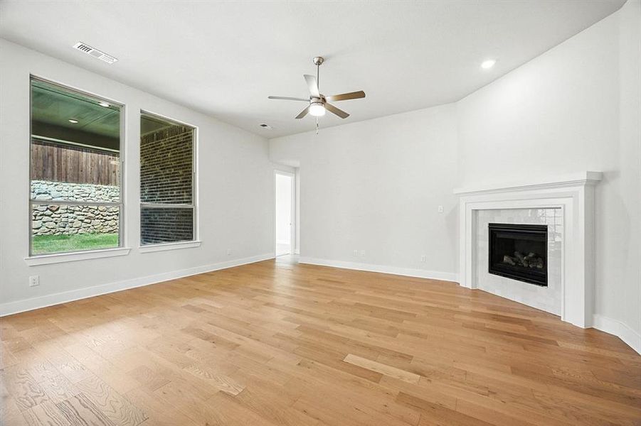Unfurnished living room featuring a tiled fireplace, light wood finished floors, ceiling fan, and recessed lighting Unfurnished living room featuring a tiled fireplace, light wood finished floors, ceiling fan, and recessed lighting