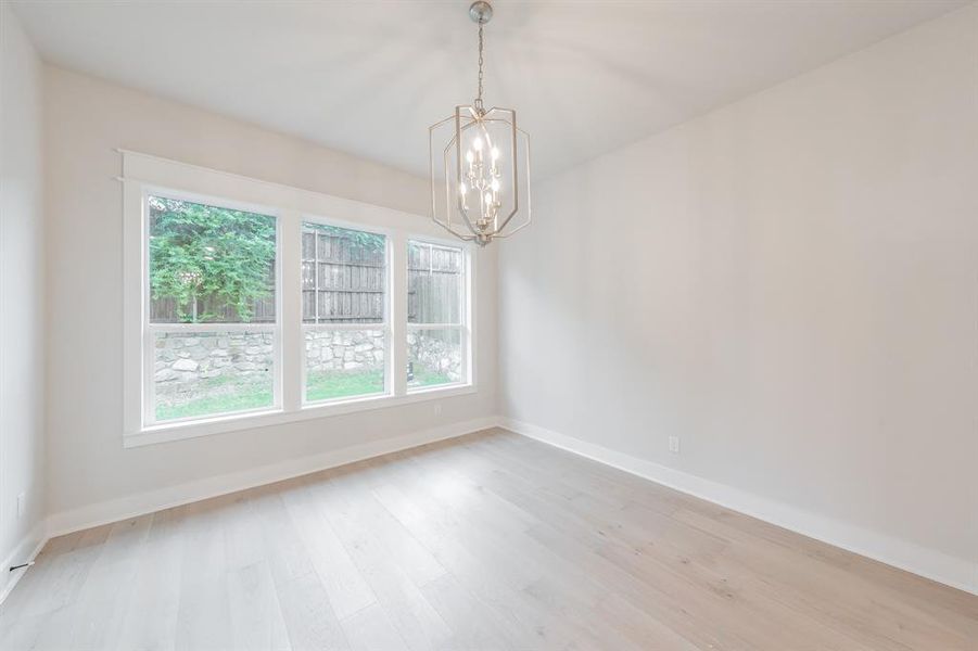 Empty room featuring light wood-type flooring and a chandelier