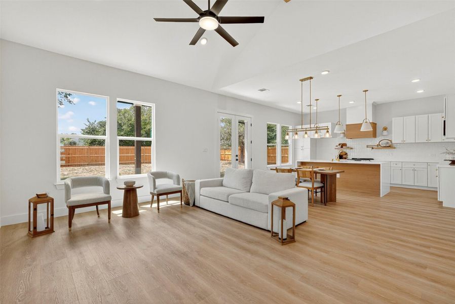 Living room with light wood-type flooring, ceiling fan, high vaulted ceiling, and recessed lighting