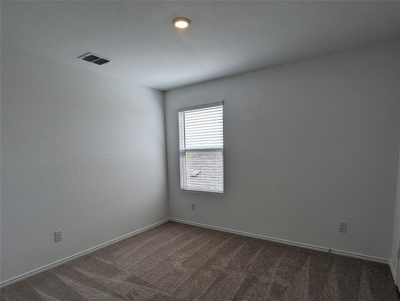 A well-lit room offers comfort with plush carpeting and natural light filtering through window blinds.