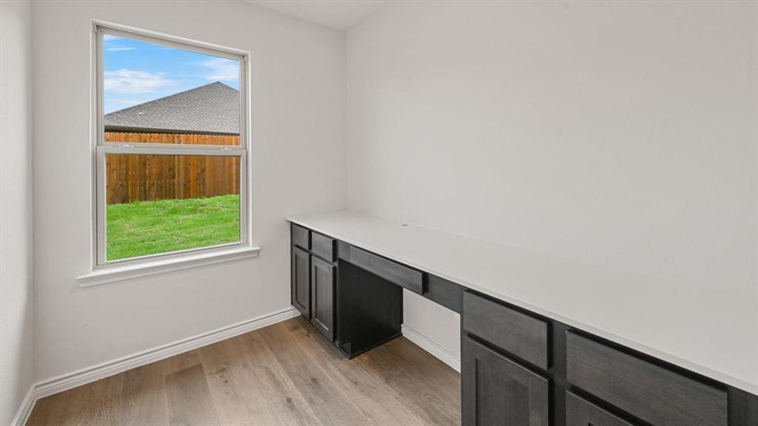 Built-in desk featuring a light-toned countertop and dark wood-finish cabinetry Built-in desk featuring a light-toned countertop and dark wood-finish cabinetry