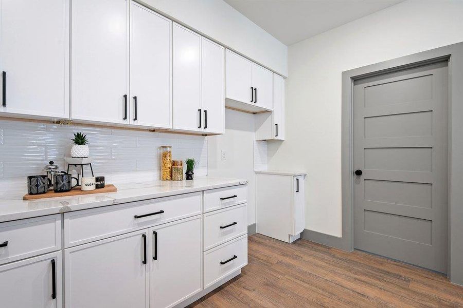 Bar area with white cabinetry, dark wood-style floors, light stone countertops, and backsplash