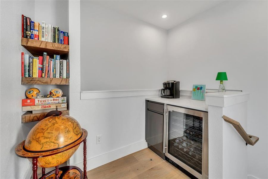 Bar with beverage cooler, light wood-style floors, light countertops, and recessed lighting Bar with beverage cooler, light wood-style floors, light countertops, and recessed lighting