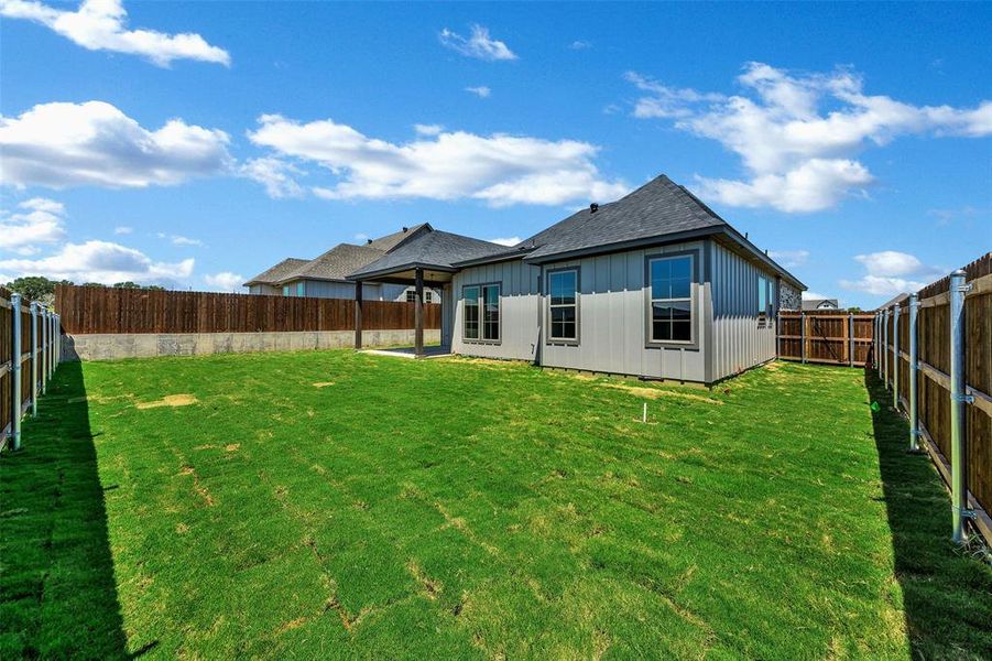 Back of property with a shingled roof, a fenced backyard, board and batten siding, and a patio area