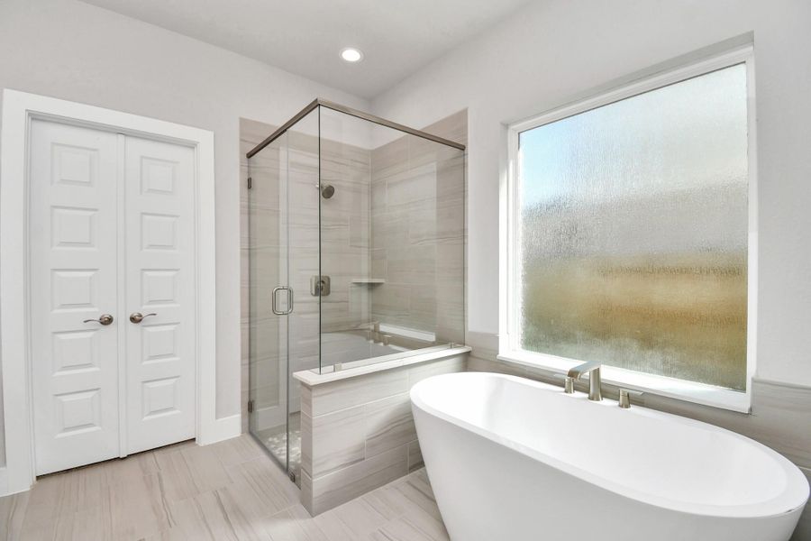 Indulge in a spa-like retreat within the confines of this primary bathroom. Delight in a spacious walk-in shower enveloped in stylish tile surround and unwind in a separate garden tub adorned with custom detailing. Sample photo of completed home with similar floor plan. Actual colors and selections may vary. Indulge in a spa-like retreat within the confines of this primary bathroom. Delight in a spacious walk-in shower enveloped in stylish tile surround and unwind in a separate garden tub adorned with custom detailing. Sample photo of completed home with similar floor plan. Actual colors and selections may vary.
