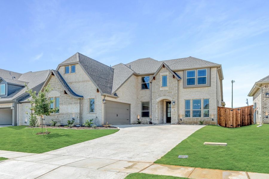 Two-story home with light stone exterior, two-car garage, and manicured front lawn