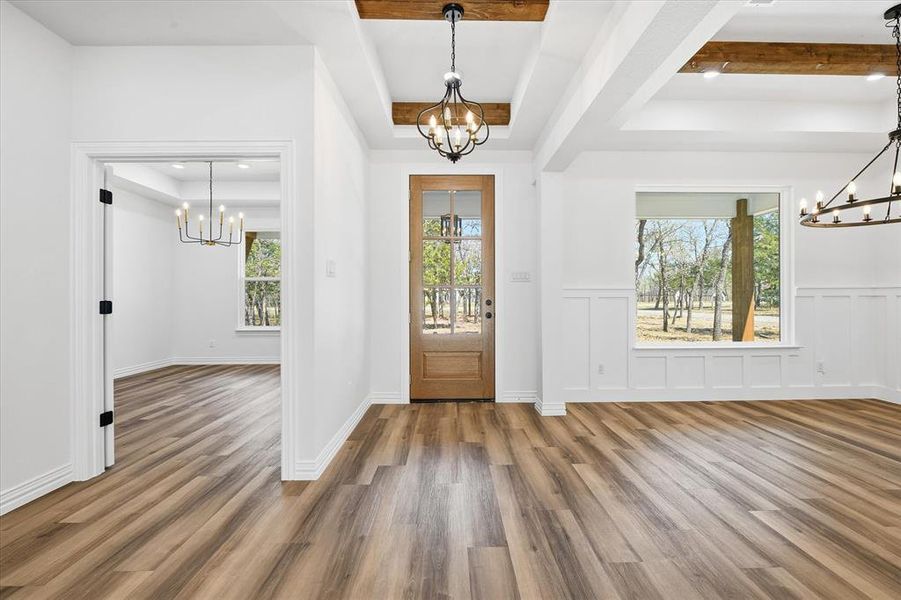 Foyer featuring a chandelier, a decorative wall, wood finished floors, wainscoting, and a tray ceiling