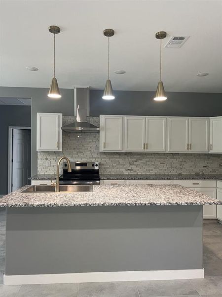 Kitchen featuring tasteful backsplash, wall chimney exhaust hood, electric range, and white cabinets. Kitchen featuring tasteful backsplash, wall chimney exhaust hood, electric range, and white cabinets.