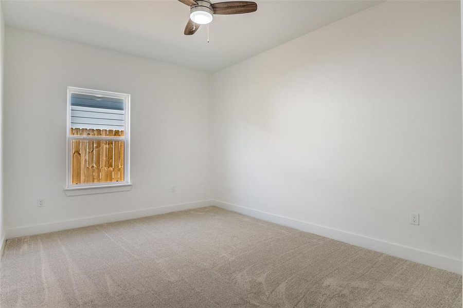 Empty room with carpet flooring and a ceiling fan Empty room with carpet flooring and a ceiling fan