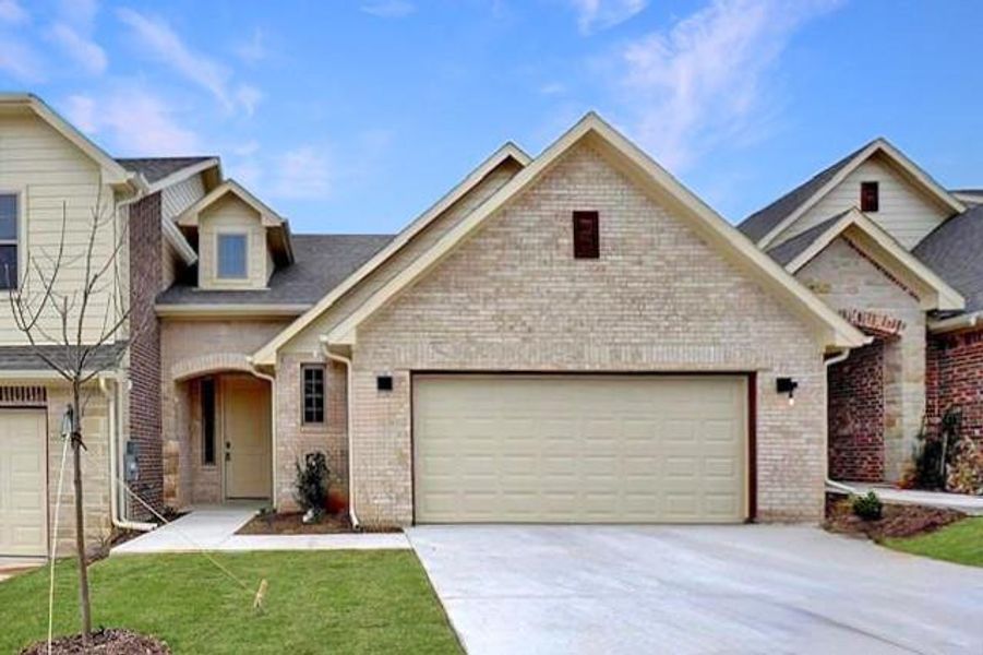 View of front of property featuring driveway, brick siding, a front yard, and a garage