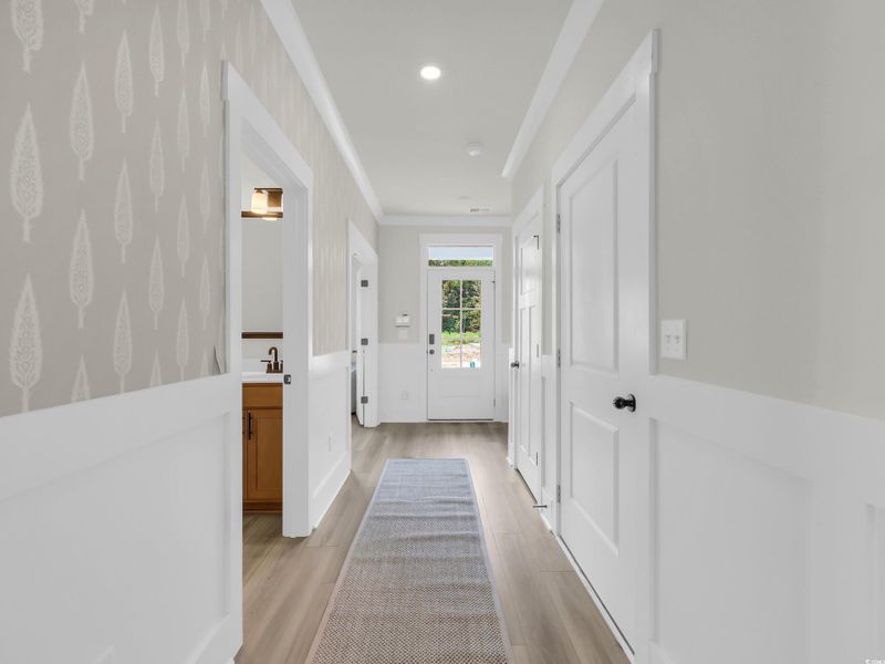 Hall with light wood-style floors, wallpapered walls, and recessed lighting