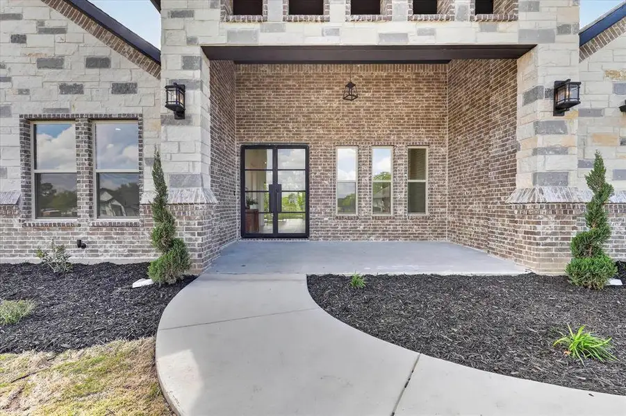 Doorway to property with brick siding and a patio