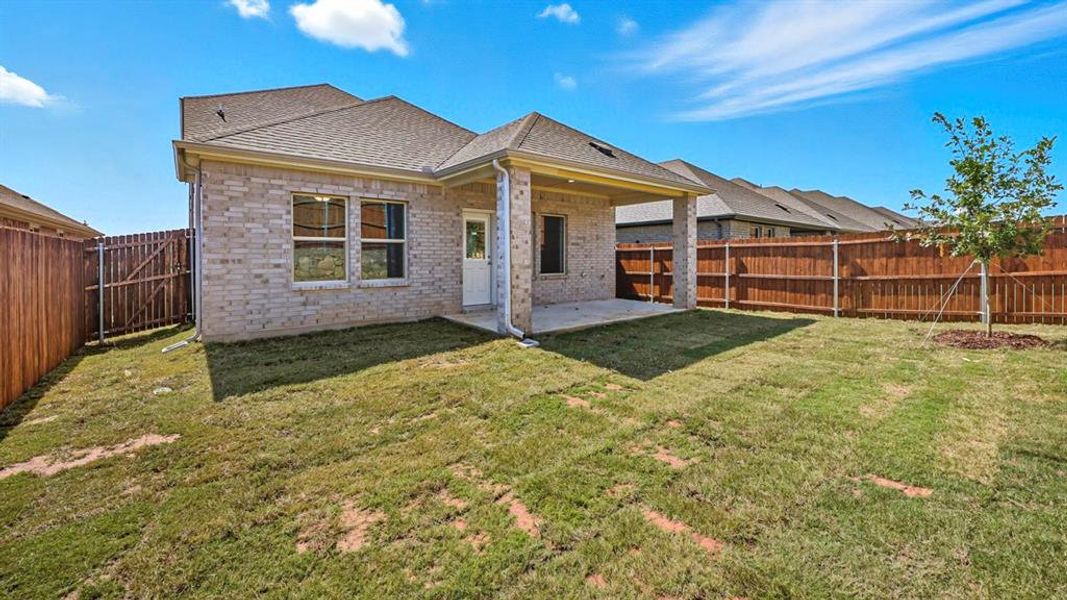 Back of house with a patio area, brick siding, roof with shingles, and a fenced backyard