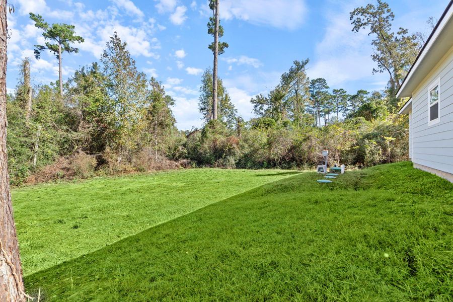 The yard provides plenty of room for outdoor activities, while the covered patio creates a comfortable spot to relax and enjoy the quiet, nature-filled surroundings.