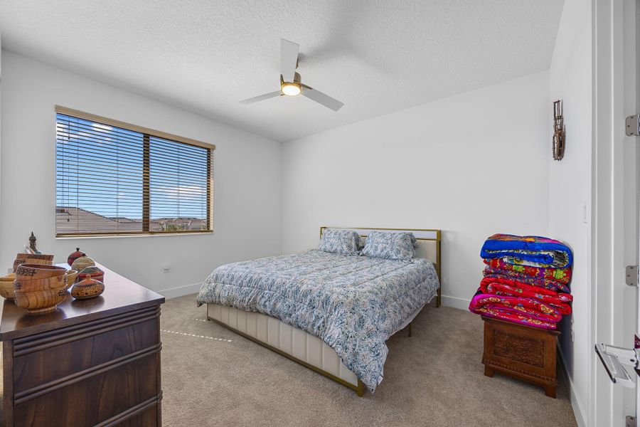 Bedroom with carpet flooring, a textured ceiling, and ceiling fan