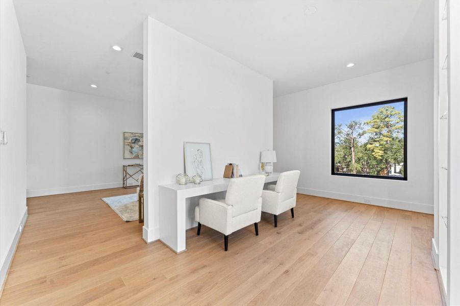 This bright home office features sleek hardwood floors, a large window with scenic views, and modern minimalist decor, creating a serene workspace.