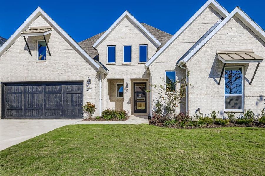 View of front of home with brick siding, a front yard, a garage, and driveway View of front of home with brick siding, a front yard, a garage, and driveway