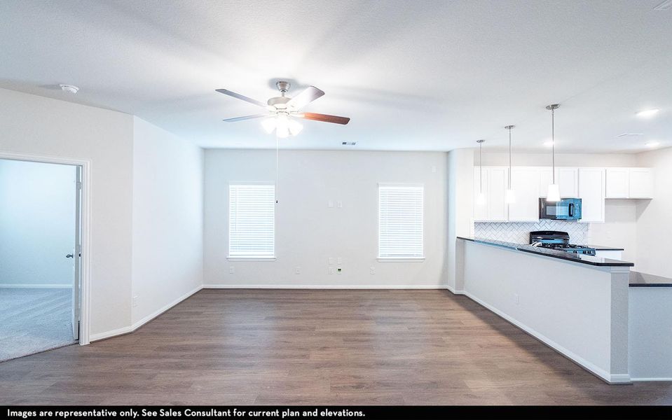 Kitchen with tasteful backsplash, black microwave, ceiling fan, stove, and wood finished floors