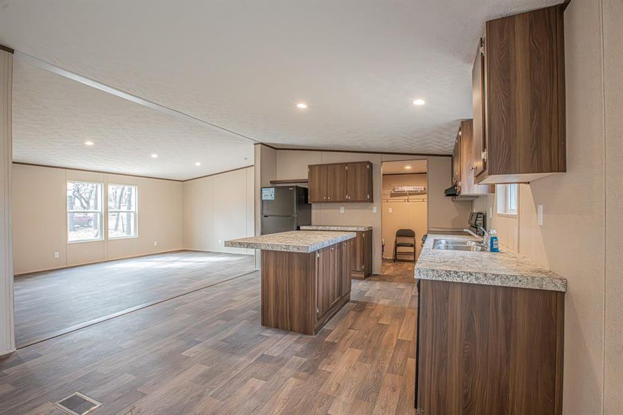 Kitchen with a center island, lofted ceiling, sink, dark hardwood / wood-style floors, and stainless steel refrigerator Kitchen with a center island, lofted ceiling, sink, dark hardwood / wood-style floors, and stainless steel refrigerator